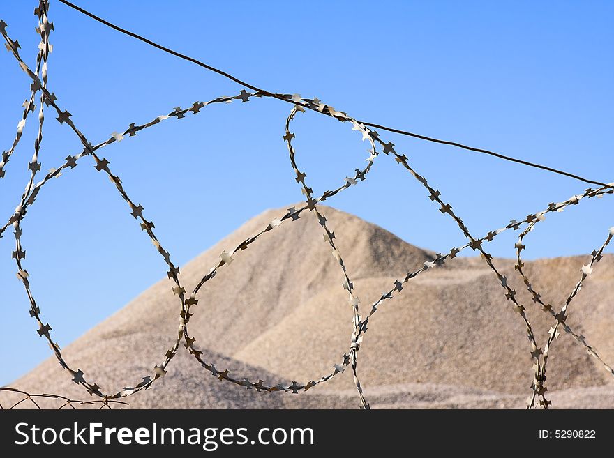 Desert hill after barbed wire on blue sky in background. Desert hill after barbed wire on blue sky in background