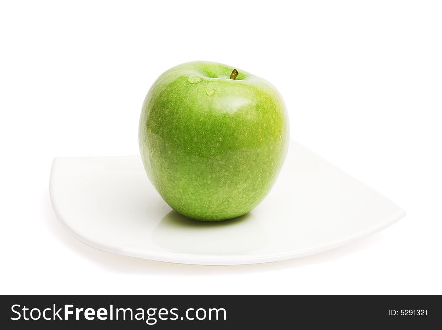 Green apple on white ceramic plate, isolated, with clipping path