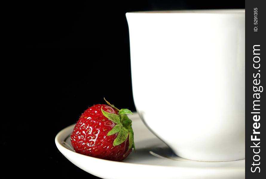 Cup of coffee and strawberry on a black background