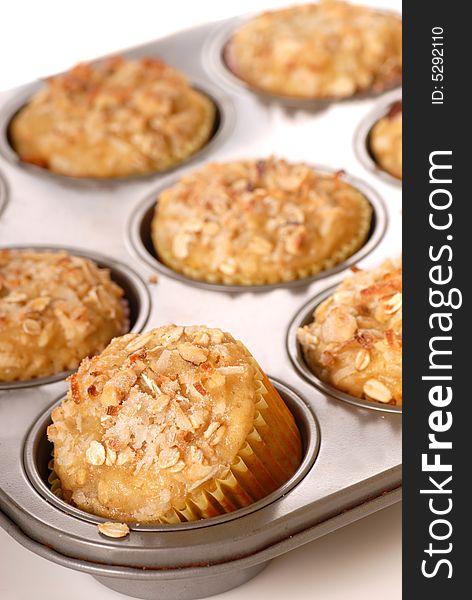 A muffin pan of freshly baked tropical pineapple muffins with coconut and nuts. A muffin pan of freshly baked tropical pineapple muffins with coconut and nuts