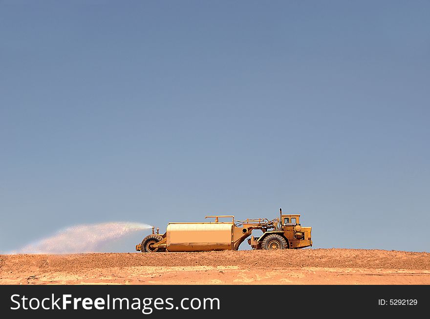 Large water truck watering down dirt on a construction pad