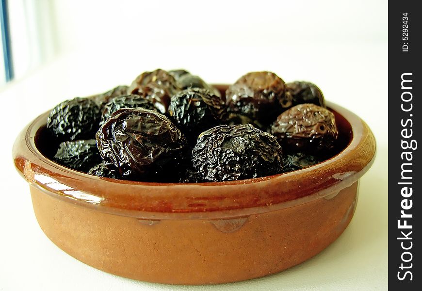 Bunch of dried black olives on a clay plate.