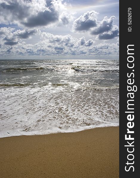 Beach seascape with puffy clouds water and sand