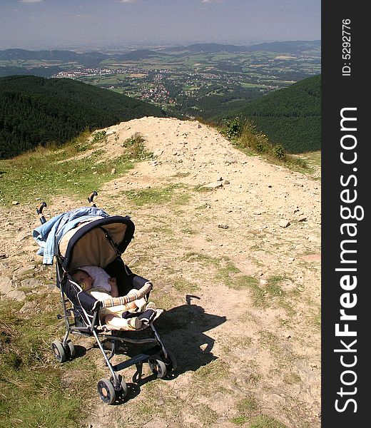 A view of a baby stroller with child on the edge of a high scenic overlook.
