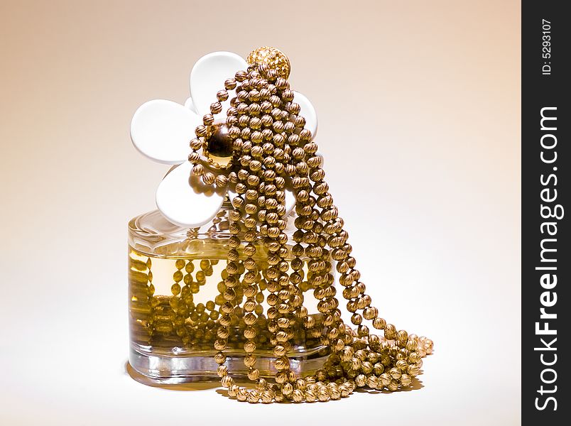 A bottle of perfume with gold necklace. A bottle of perfume with gold necklace.