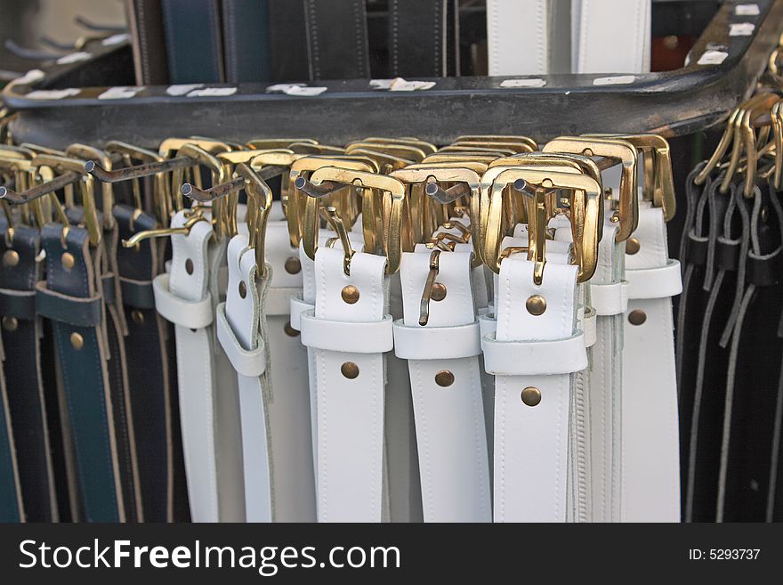 A close up shot of leather belts with gold buckles on a display stand