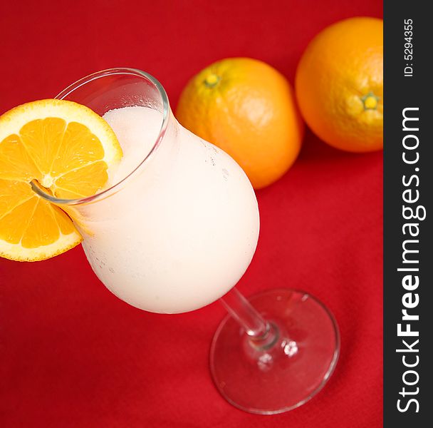 White pina colada with slice of orange on red table cloth. White pina colada with slice of orange on red table cloth