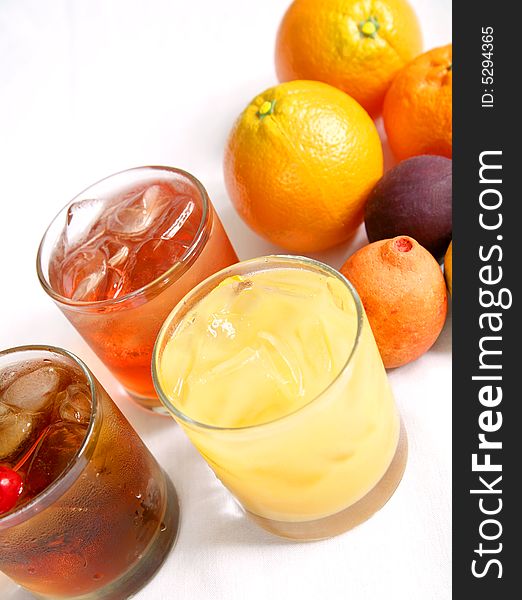 Three mixed drink on table. from left to right manhattan cocktail, malibu breeze cocktail, and screw driver cocktail. Three mixed drink on table. from left to right manhattan cocktail, malibu breeze cocktail, and screw driver cocktail