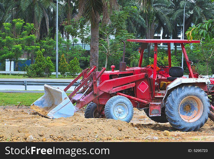 A red tractor busy with excavation work at a construction site. A red tractor busy with excavation work at a construction site