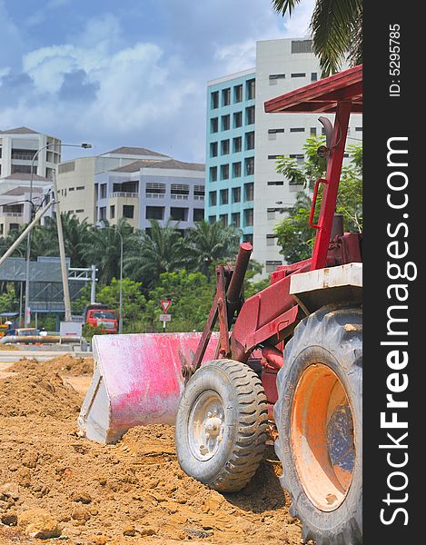A red tractor busy with excavation work at a construction site. A red tractor busy with excavation work at a construction site