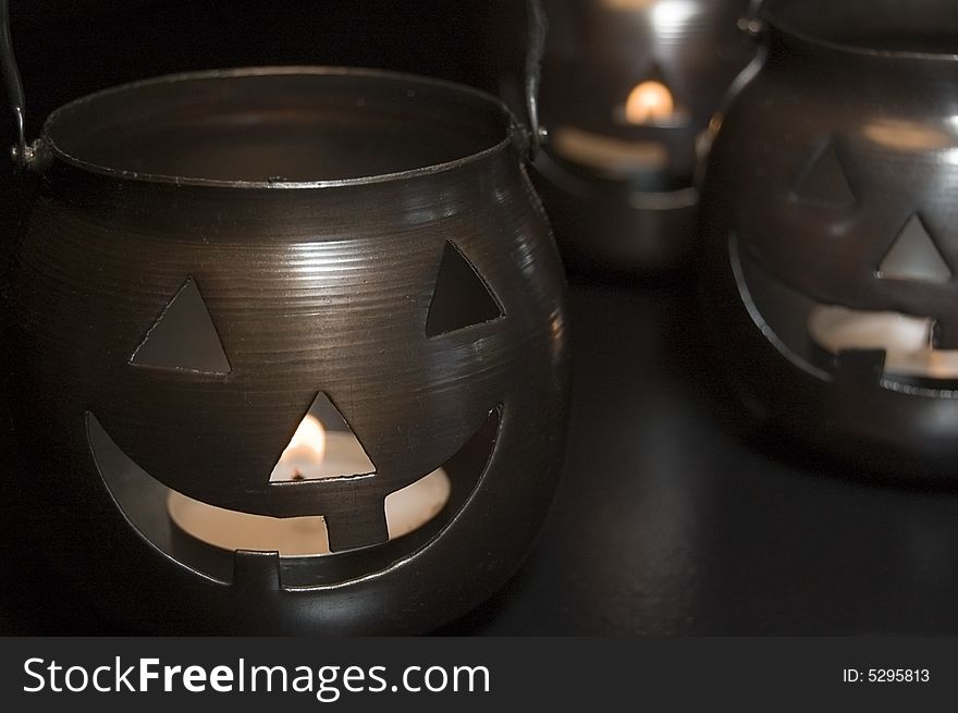 Three metal jack-o-lantern candle holders close-up.