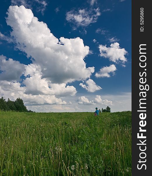 Summer landscape with green grass, blue sky and boy walking. Summer landscape with green grass, blue sky and boy walking