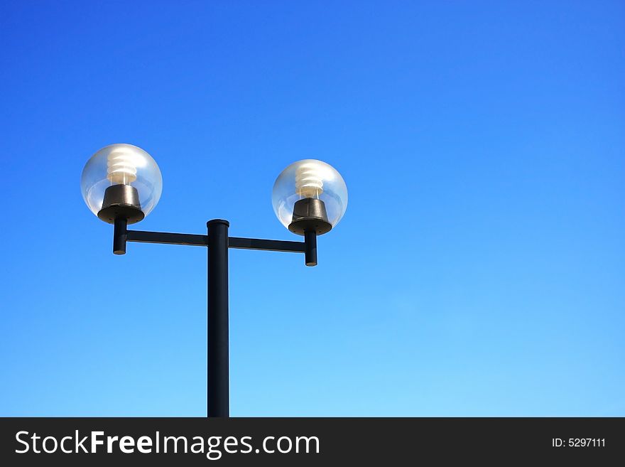 A streetlamp with two bulb over blue sky. A streetlamp with two bulb over blue sky.