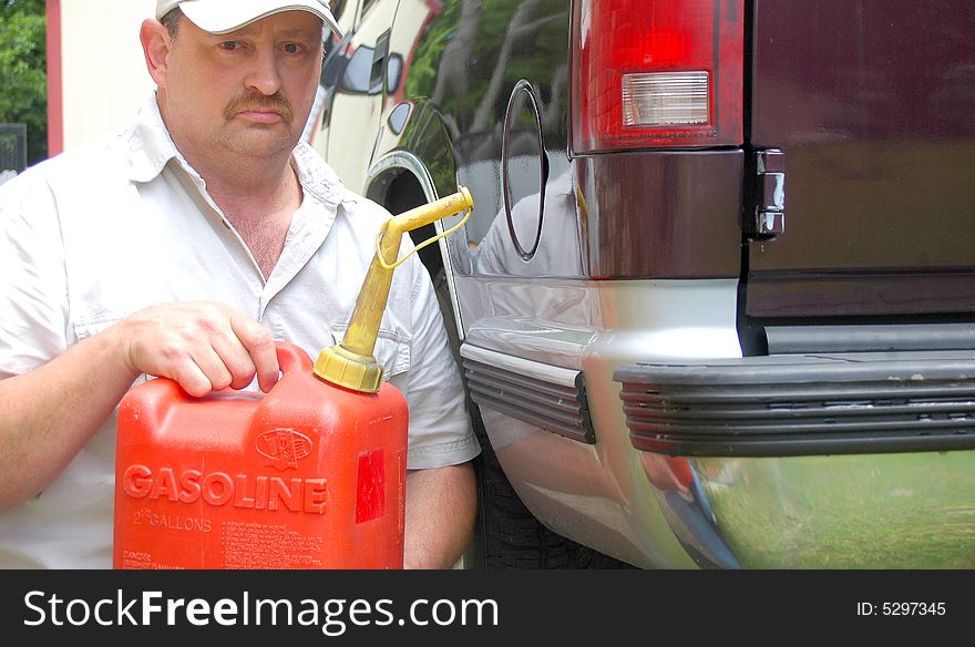 Man pouring the last two gallons of gas that he can afford into his truck. Man pouring the last two gallons of gas that he can afford into his truck.