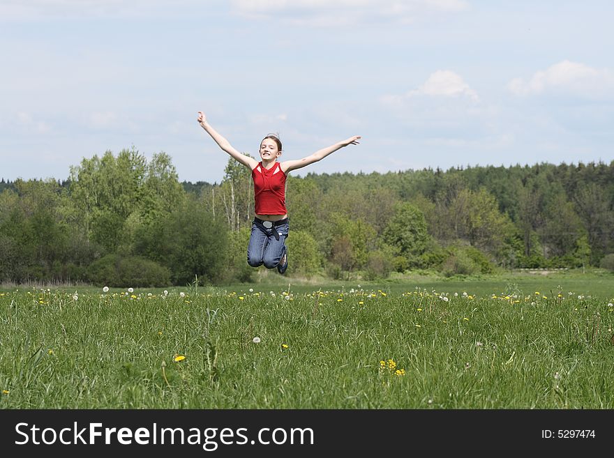 Nice young girl jumping on background with green field and blue sky. Nice young girl jumping on background with green field and blue sky