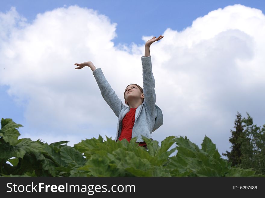 Nice young girl with hands up looking at the blue sky with clouds. Nice young girl with hands up looking at the blue sky with clouds