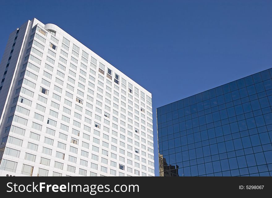 A large white hotel next to a blue glass office tower. A large white hotel next to a blue glass office tower