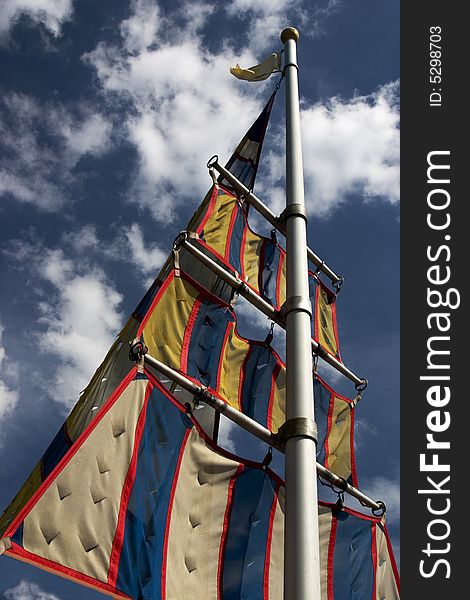 The sails of a sailboat against a blue sky with clouds. The sails of a sailboat against a blue sky with clouds