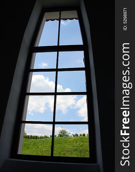 A closed window and view to a peaceful landscape with blue sky. A closed window and view to a peaceful landscape with blue sky