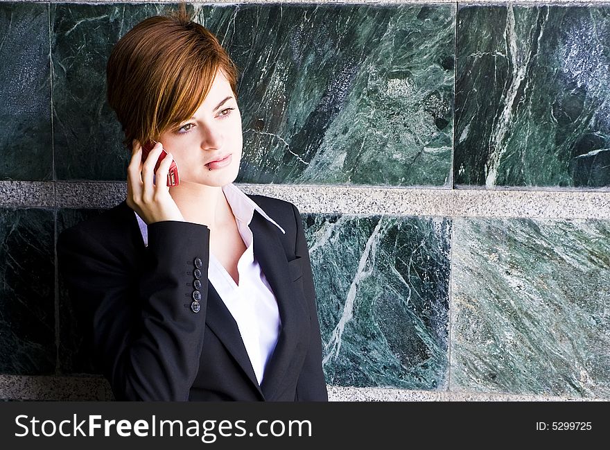 Beautiful businesswoman at phone over marble background.