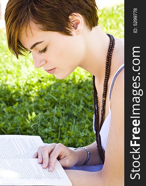 Beautiful blond woman reading over the grass