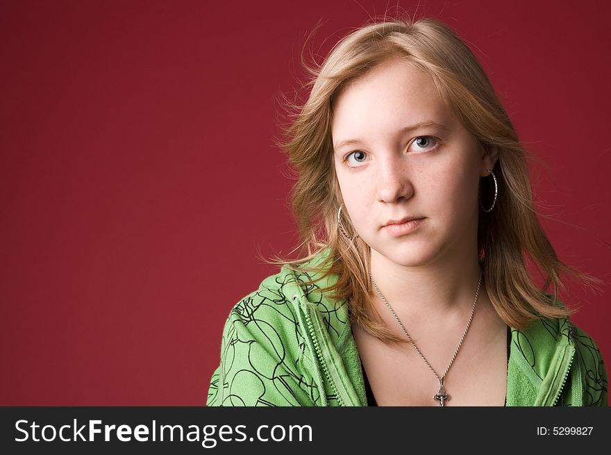 The young girl in green clothes on a red background. The young girl in green clothes on a red background.