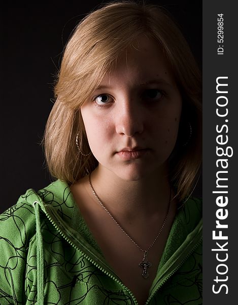 The young girl in green clothes on a black background. The young girl in green clothes on a black background.
