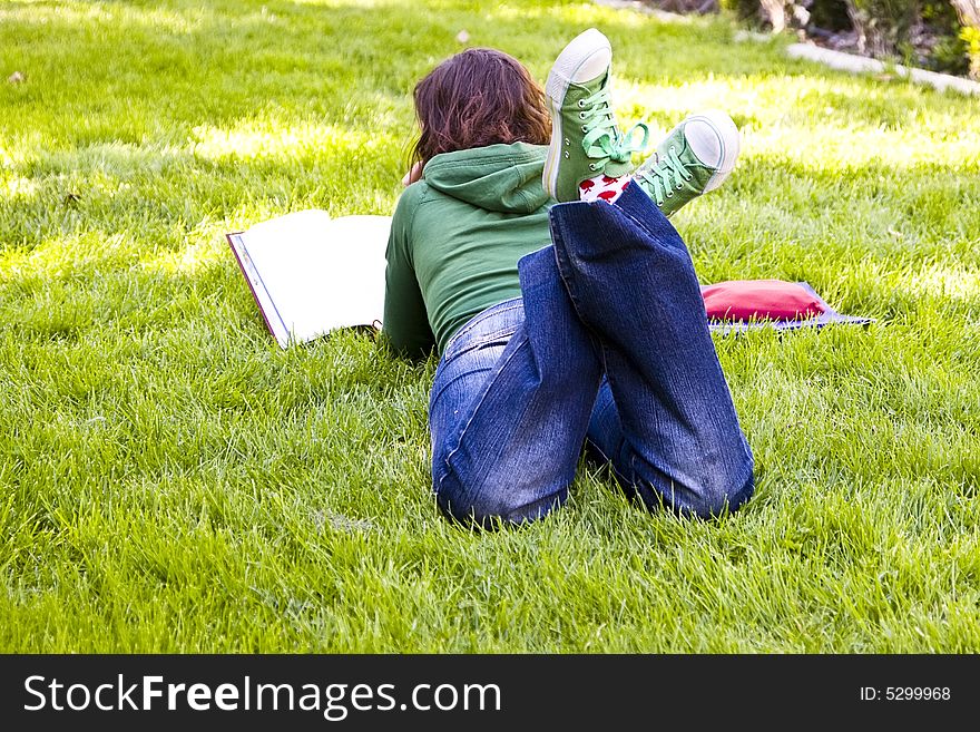 Young student reading on the grass in the park. Young student reading on the grass in the park.