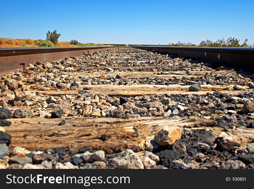 A mouse eye view of a long straight railroad track in the Mojave desert. A mouse eye view of a long straight railroad track in the Mojave desert.