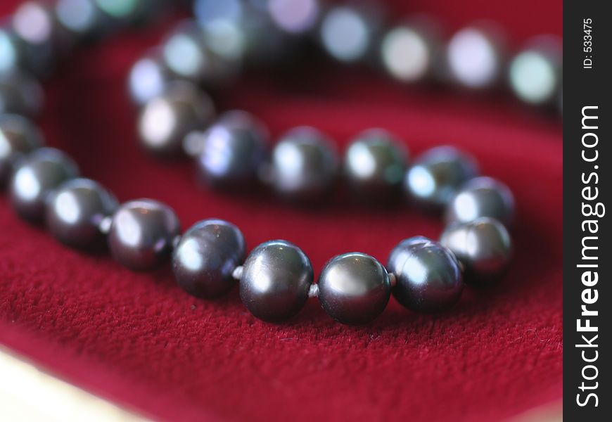 Close up of a black pearl necklace on red velvet