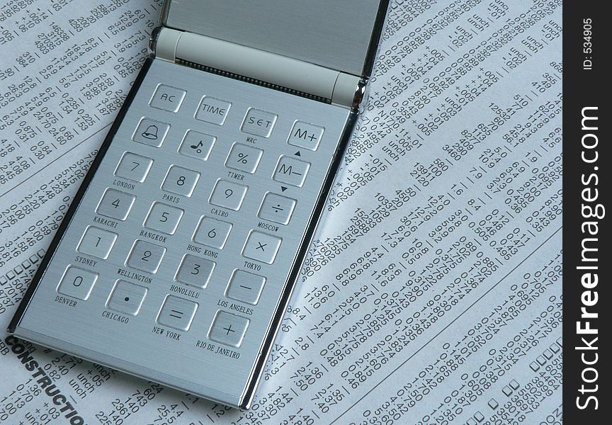 Shot of a calculator with name of cities printed on it, on a numerical newspaper background. Shot of a calculator with name of cities printed on it, on a numerical newspaper background.
