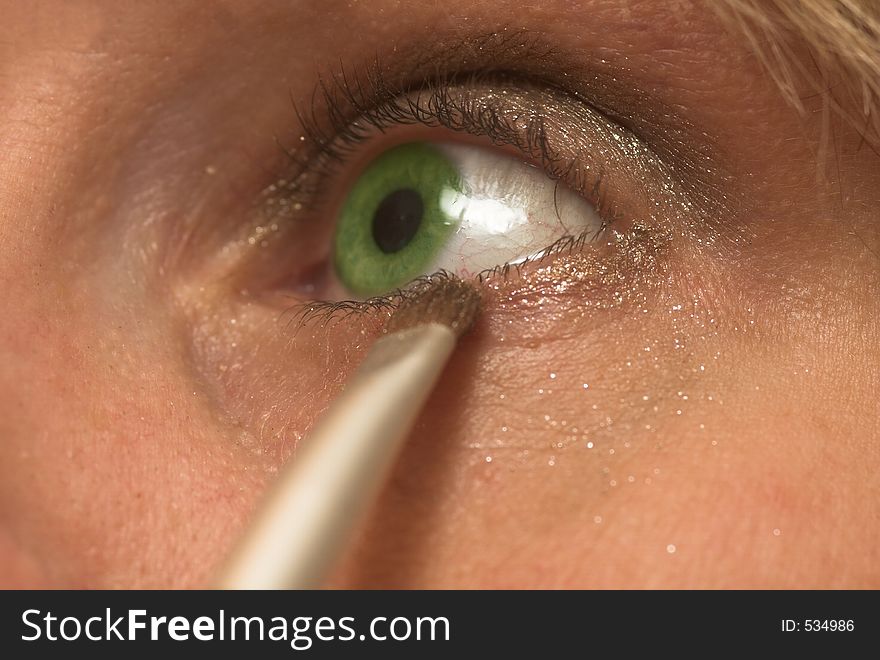Woman with green eyes painting her eyeline. Woman with green eyes painting her eyeline