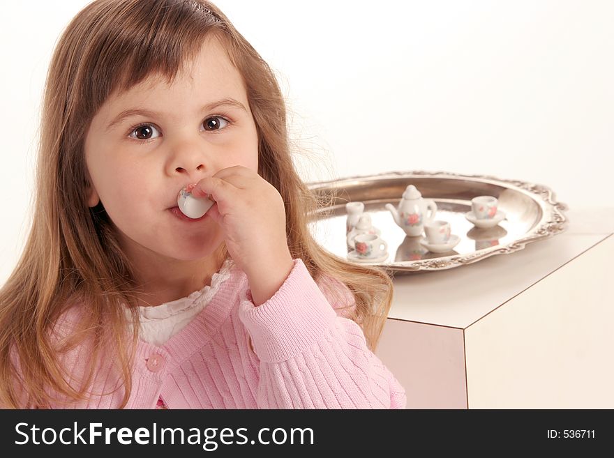 Young girl takes a sip of her tea at the tea party. Young girl takes a sip of her tea at the tea party