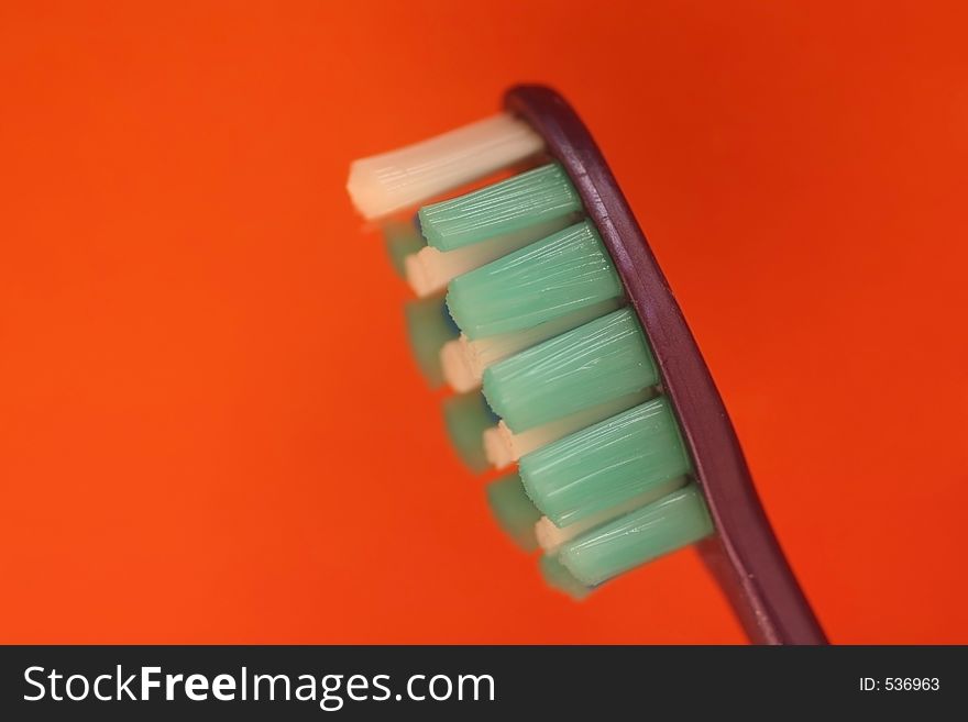 Macro of toothbrush leaning slightly isolated on orange background. Macro of toothbrush leaning slightly isolated on orange background