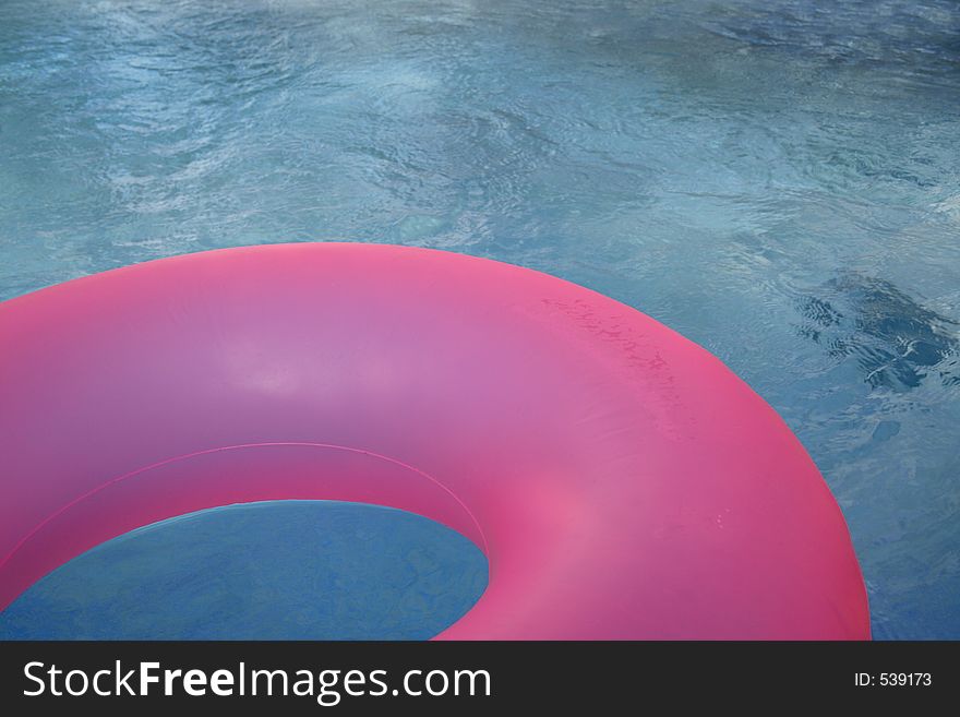 Hot pink inner tube in corner of pool. Hot pink inner tube in corner of pool