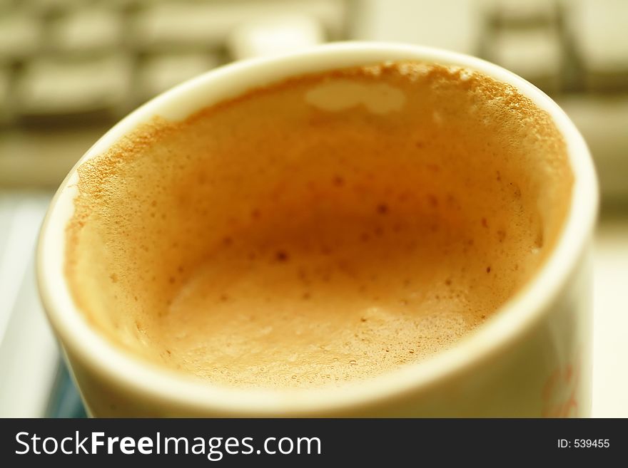 Half-drunk coffee with lots of foam & Krema. out of focus keyboard in the background. Selective focusing is intentional. Half-drunk coffee with lots of foam & Krema. out of focus keyboard in the background. Selective focusing is intentional.