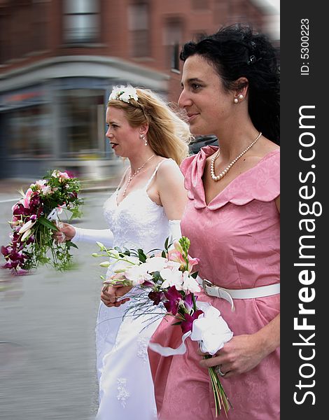 Beautiful bride and her Bride's Maid running down the street en route to the ceremony location. Beautiful bride and her Bride's Maid running down the street en route to the ceremony location