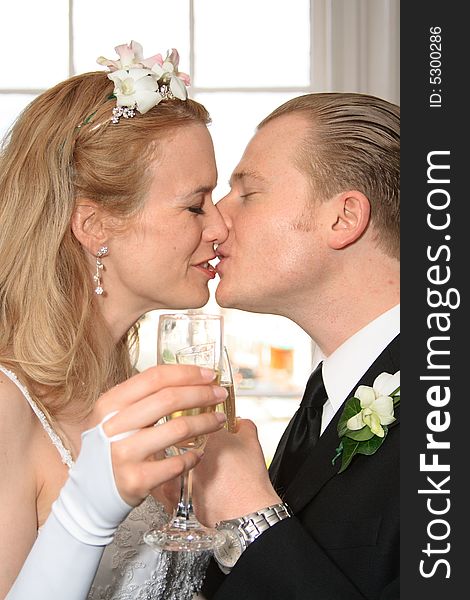 Bride and groom kissing while toasting champaign. Bride and groom kissing while toasting champaign.