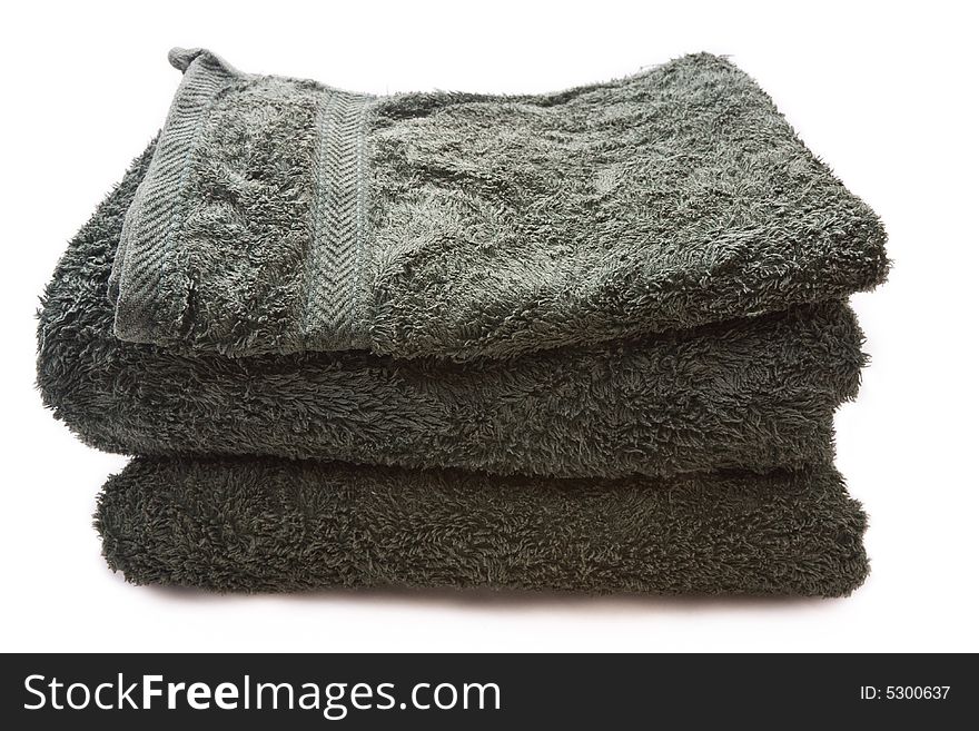 A stack of green bath towels against a white background