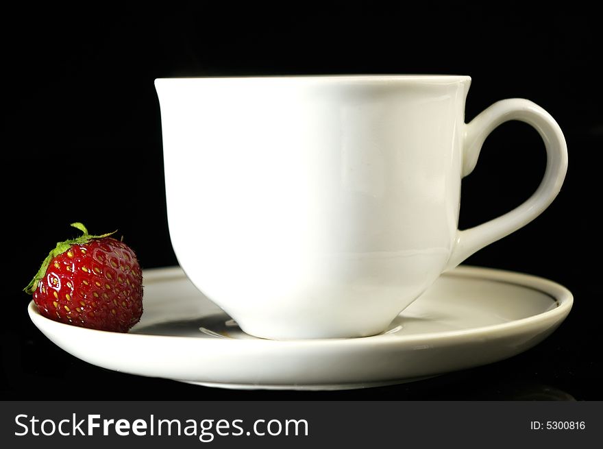 Cup of coffee and strawberry on a black background. Cup of coffee and strawberry on a black background