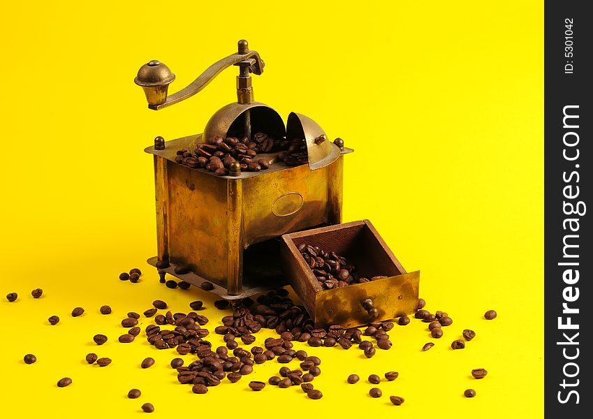 Antiquity coffee machine with beans over yellow background