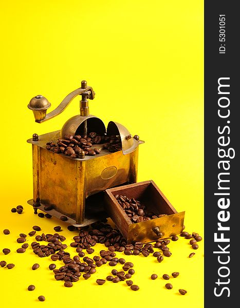 Antiquity coffee machine with beans over yellow background