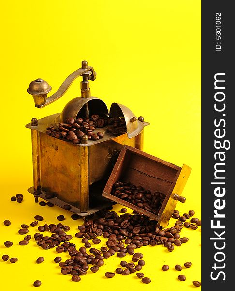 Antiquity coffee machine with beans over yellow background