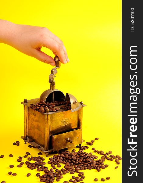 Antiquity coffee machine with beans over yellow background