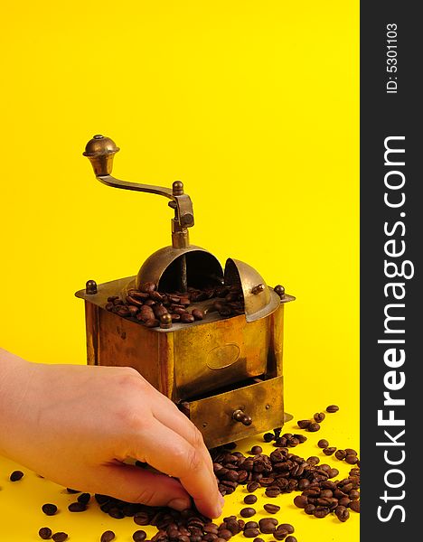 Antiquity coffee machine with beans over yellow background