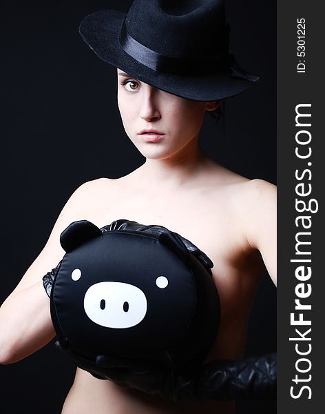 Girl in a black hat with a bag as a pig in hands. Girl in a black hat with a bag as a pig in hands