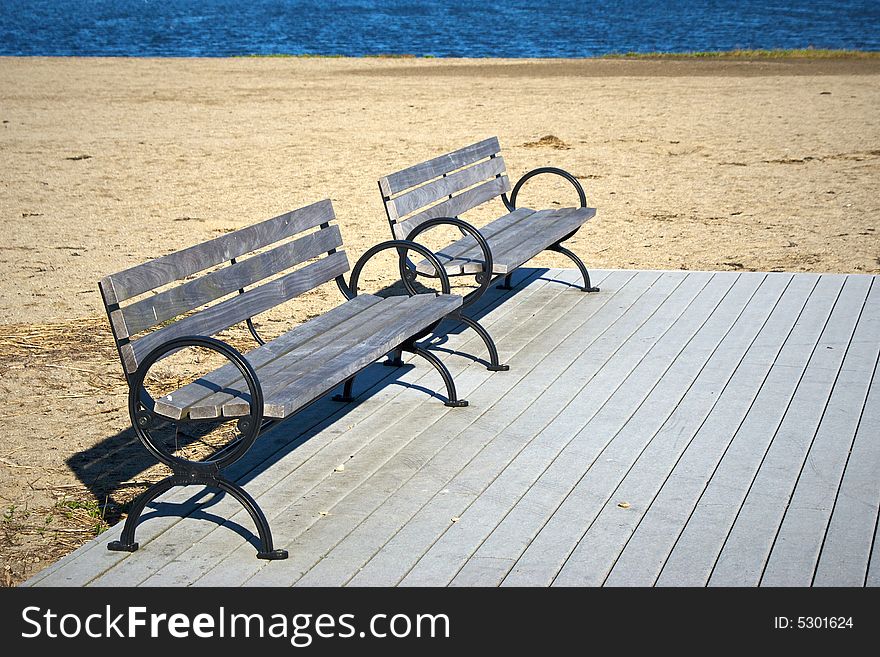 Two empty park benches on an abandoned beach on deck. Two empty park benches on an abandoned beach on deck