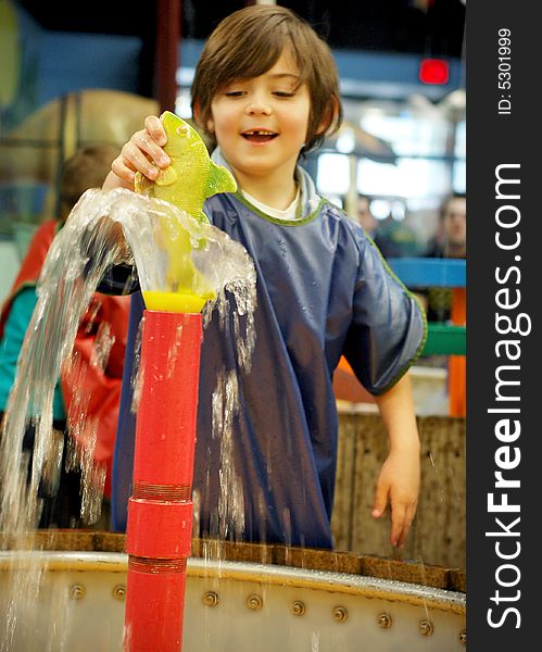 Shot of a young smiling boy, who's missing a front tooth, playing in colorful fountain. Shot of a young smiling boy, who's missing a front tooth, playing in colorful fountain.