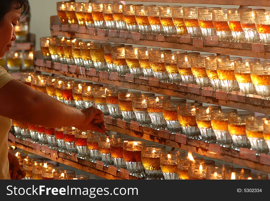 A volunteer helping to keep the flames of the wesak day oil lamp burning. A volunteer helping to keep the flames of the wesak day oil lamp burning