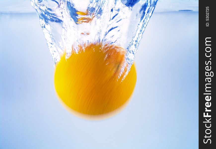 Close-up of water waving and splashing caused by spinning dropping orange. Close-up of water waving and splashing caused by spinning dropping orange